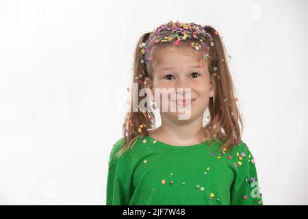 Portrait d'un enfant confus après une pluie confetti avec des guirlandes multicolores et des confettis. S'amuser à célébrer son anniversaire. Banque D'Images