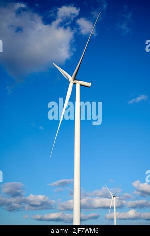 Éolienne simple contre le ciel bleu et les nuages. Banque D'Images