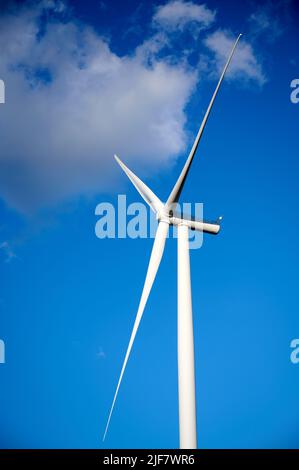 Éolienne simple contre le ciel bleu et les nuages. Banque D'Images