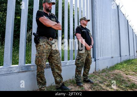 30 juin 2022, Nowodziel, Pologne: Les gardes-frontières se tiennent aux barrières physiques construites à la frontière entre la Pologne et la Biélorussie. La barrière a été construite au cours des deux premiers trimestres de 2022. Le gouvernement polonais a décidé de construire une barrière en acier de 186 kilomètres de long et de 5,5 mètres de haut avec des barbelés à la frontière entre la Pologne et la Biélorussie, qui est aussi la frontière de l'Union européenne et de l'OTAN. La décision a été prise après que des milliers de migrants, principalement originaires de Syrie, d'Iraq et d'Afghanistan, aient tenté de traverser la Pologne depuis le Bélarus. Le gouvernement du Bélarus a été accusé d'orchestrer la migration, avec l'aide Banque D'Images