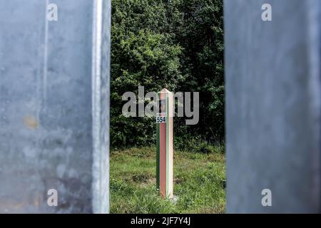 30 juin 2022, Nowodziel, Pologne: Le pôle frontalier bélarussien est vu derrière une barrière métallique lors d'une conférence de presse qui marque la fin de la construction des barrières physiques entre la Pologne et la Biélorussie. Le gouvernement polonais a décidé de construire une barrière en acier de 186 kilomètres de long et de 5,5 mètres de haut avec des barbelés à la frontière entre la Pologne et la Biélorussie, qui est aussi la frontière de l'Union européenne et de l'OTAN. La décision a été prise après que des milliers de migrants, principalement originaires de Syrie, d'Iraq et d'Afghanistan, aient tenté de traverser la Pologne depuis le Bélarus. Le gouvernement du Bélarus a été accusé d'orchestrer le ratio de migration Banque D'Images