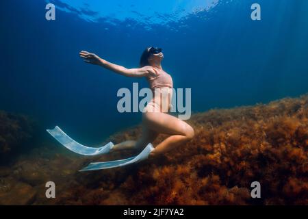 Fille de freediver posant sous l'eau sur les profondeurs de la mer bleue Banque D'Images