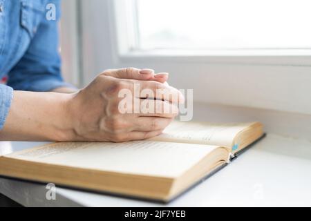 Les mains pliées dans la prière sur une Sainte Bible pour la foi, la spiritualité et la religion, la femme priant sur la sainte bible le matin Banque D'Images
