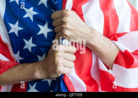 Le jeune homme priant en nous portant le drapeau en mettant la main sur le coeur - concept de contemplation et de liberté. Banque D'Images