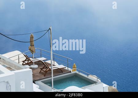 Deux chaises longues à côté d'une petite piscine et une vue imprenable sur la mer Égée à Santorin Banque D'Images