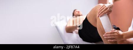 Close-up de la thérapeute de l'homme Epilation jambe avec bande de cire Banque D'Images