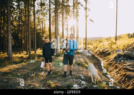 Parents avec son fils et chien de compagnie marchant dans la forêt Banque D'Images