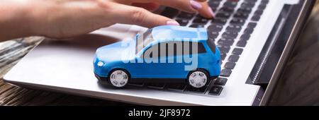 Femme d'affaires travaillant sur un ordinateur portable avec une petite voiture bleue Banque D'Images