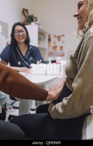 Main de l'homme touchant l'estomac de la femme enceinte en clinique Banque D'Images