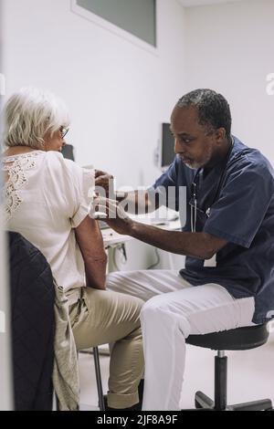 Un médecin de sexe masculin mature examine une patiente senior en clinique médicale Banque D'Images