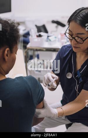 Femme gynécologue portant des lunettes injectant le patient pendant la FIV en clinique médicale Banque D'Images