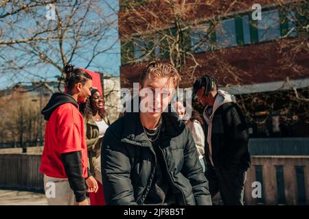 Portrait du jeune homme avec des amis en arrière-plan le jour ensoleillé Banque D'Images