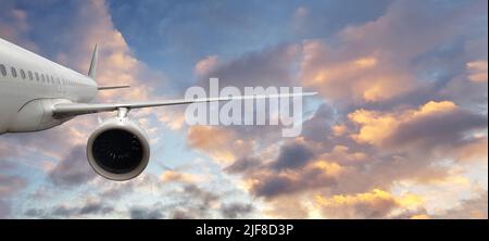 Avion blanc commercial volant au-dessus des nuages dans une lumière de coucher de soleil spectaculaire. Concept de voyage et de transport Banque D'Images