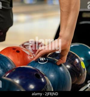 Gros plan d'une main qui saisit une boule de bowling Banque D'Images