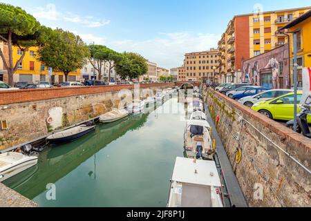 Des bateaux bordent les canaux bondés à côté de la nouvelle forteresse et un café extérieur en bord de mer dans la ville toscane de Livourne, en Italie. Banque D'Images