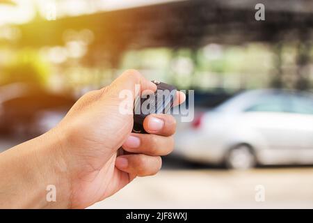 La main de l'homme appuie sur la commande à distance des systèmes d'alarme de voiture Banque D'Images