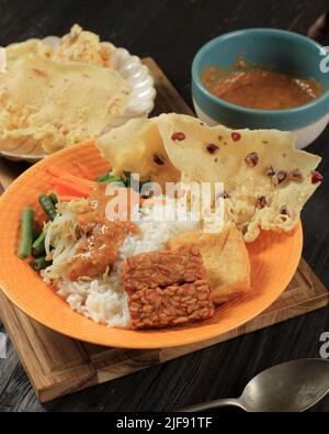 Nasi Pecel, menu traditionnel indonésien avec sauce piquante aux cacahuètes, tempeh, légumes durs et tofu frits, Rempeyek,Populaire pour le petit déjeuner, le dîner, ou Banque D'Images