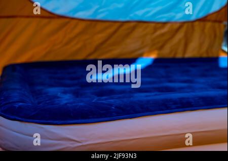 Mise au point sélective d'un matelas pneumatique gonflable sur le sol d'une tente en cours de remplissage. Banque D'Images