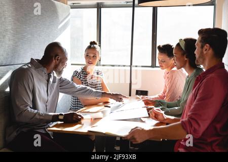 Des collègues d'affaires multiraciaux discutent du plan d'affaires lors d'une réunion dans un bureau de création Banque D'Images