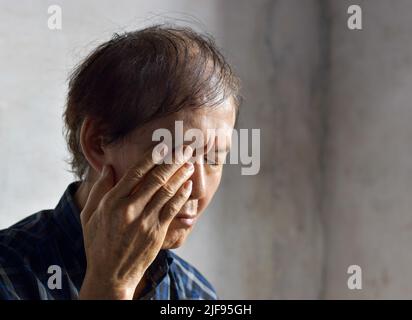 Homme asiatique aîné frottant les yeux. Concept de la fatigue oculaire ou de la démangeaison de la paupière. Banque D'Images