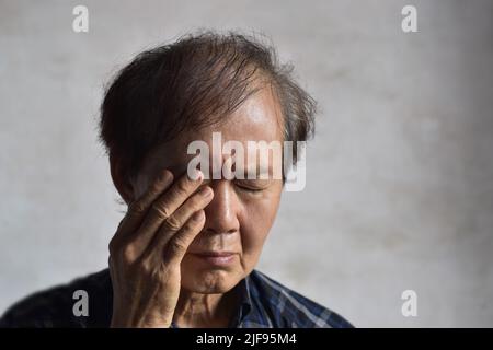 Homme asiatique aîné frottant les yeux. Concept de la fatigue oculaire ou de la démangeaison de la paupière. Banque D'Images