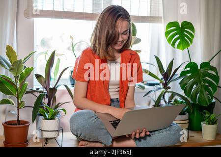 Happy caucasiens adolescent lycée étudiant avec ordinateur portable faire des recherches en ligne devoirs, souriant adolescente femme utilisant l'ordinateur pour l'éducation en ligne. Apprentissage et travail à distance. Banque D'Images