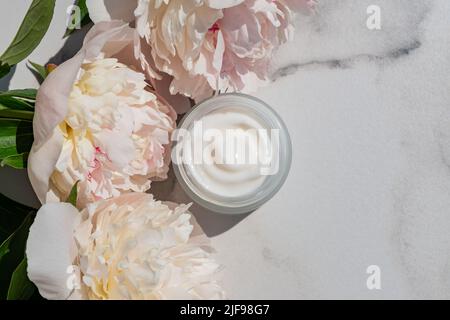 Jarre blanche sans marque et fleurs de pivoine rose sur fond de table en marbre. Bouteille pour marquage et étiquette. Cosmétiques naturels bio spa. Espace de copie, Banque D'Images