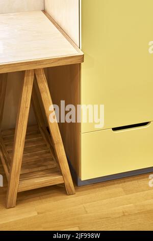 Fragment de table pour enfants avec armoire en contreplaqué et supports en chêne massif près de l'armoire jaune. Meubles en bois pour chambre à coucher de fermeture intérieure Banque D'Images