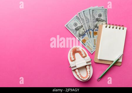 Composition de pose à plat avec modèle de typographie dentaire pédagogique et argent avec carnet sur table colorée, vue de dessus. Traitement coûteux. Banque D'Images