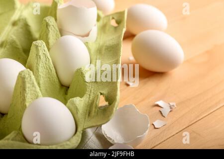 Support en carton avec œufs de poulet et coquilles sur fond en bois, gros plan Banque D'Images