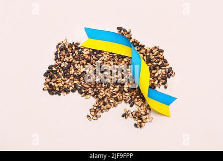 Grains de blé et rubans aux couleurs du drapeau ukrainien sur fond clair Banque D'Images