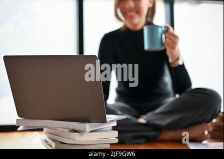 Femme auteur indépendant ayant un café du matin tout en travaillant et en utilisant l'ordinateur portable. Image rognée et foyer sélectif Banque D'Images