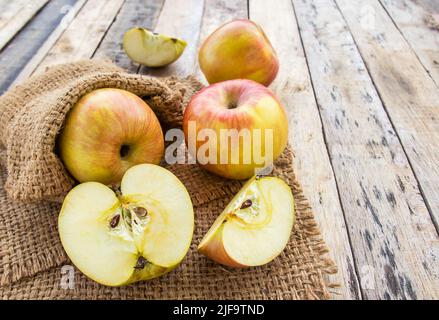 Pommes fraîches dans un sac à burlap sur fond de table en bois Banque D'Images