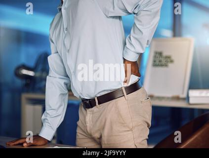 Gros plan un jeune africain se tenant dans la douleur et debout à son bureau tard dans la nuit dans son bureau. Homme d'affaires afro-américain souffrant de mal Banque D'Images