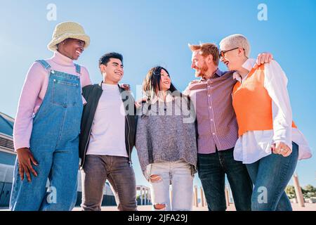 Portrait d'amis heureux debout avec les bras autour des épaules de l'autre. Groupe d'amis multiraciaux s'amuser ensemble en plein air Banque D'Images