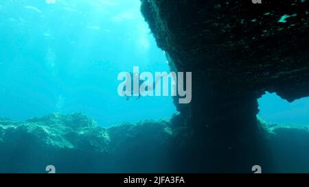 Une femelle plongée sous-marine nagent près de la sortie de la grotte. Plongée sous-marine en mer Méditerranée, Chypre Banque D'Images