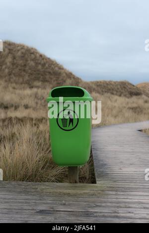 Poubelle vert clair avec pictogramme dans les dunes de sable d'Amrum (Allemagne) à côté d'une promenade un après-midi en hiver Banque D'Images