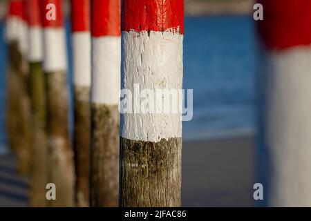 Marqueurs rouges et blancs en bois peint dans le lagon. Banque D'Images