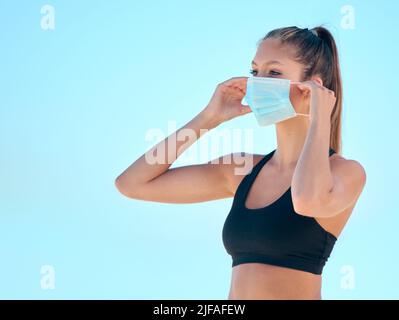 Belle femme faisant de l'exercice de yoga tout en portant un masque. Jeune athlète féminine se tenant sur la plage pendant l'entraînement à l'extérieur. Arrêter l'épandage de Banque D'Images
