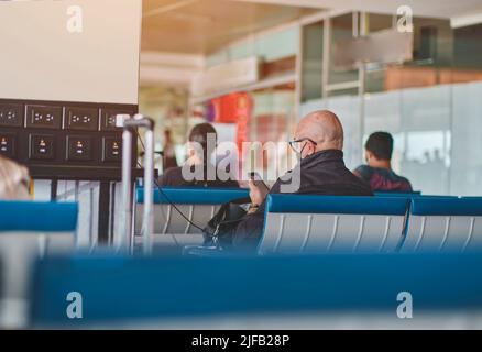 Homme expérimenté avec appareils de charge de smartphone dans le salon de l'aéroport avec chariot à bagages. Mise au point sélective, Travel concept. Banque D'Images