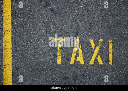 Ligne jaune et panneau de taxi sur la route asphaltée rugueuse de la ville. Banque D'Images