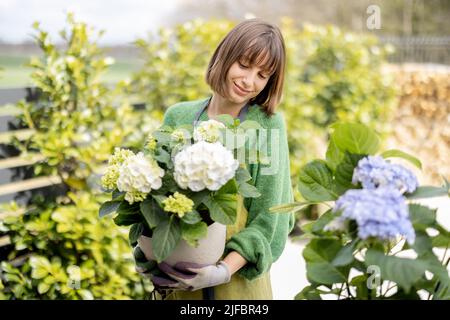 Jeune femme prenant soin des fleurs dans le jardin Banque D'Images