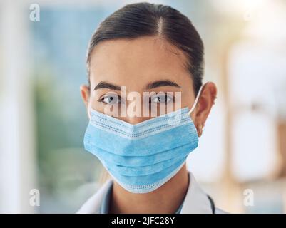 Jeune infirmière de race mixte portant un masque pour se protéger de la maladie de covid pendant qu'elle travaille à l'hôpital. Portrait d'une jeune femme hispanique Banque D'Images
