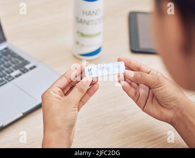 Gros plan d'une femme méconnaissable d'une race mixte tenant un kit de test rapide. Une employée de bureau qui tient un kit de test de virus corona au travail pour Banque D'Images