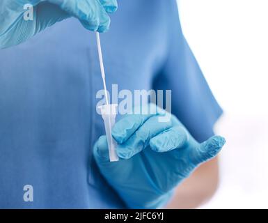 Médecin méconnaissable portant des gants et tenant un coton-tige tout en se tenant contre un fond blanc de studio. gp non reconnaissable se préparant à utiliser un Banque D'Images