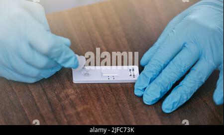 Médecin méconnaissable portant des gants et préparant un test de covid sur une table pendant son travail à l'hôpital. Gros plan d'un gp non reconnaissable travaillant sur un Banque D'Images