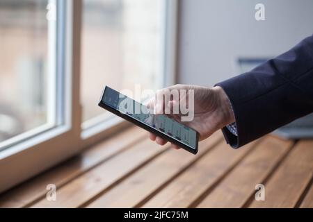 Image en gros plan d'un smartphone à main masculine avec écran blanc vierge. Les mains de l'homme avec le téléphone portable dans la lumière du jour. Affichage vide Banque D'Images