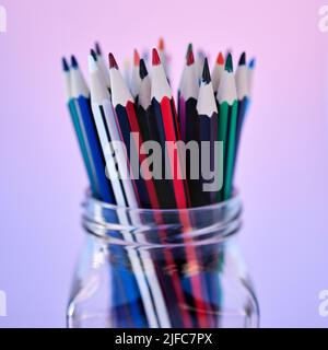 Gros plan de nombreux crayons dans un pot en verre isolé sur un fond coloré. Vue macro de la papeterie pour l'art et le dessin. Fournitures scolaires pour un étudiant Banque D'Images