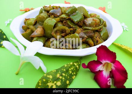 Délicieux cari au poivron vert ou au poivron vert. Remuez avec des oignons sautés sabaji asiatique indien avec du masala. Sur fond rouge, l'image de la nourriture est un espace de copie de Banque D'Images