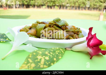 Délicieux cari au poivron vert ou au poivron vert. Remuez avec des oignons sautés sabaji asiatique indien avec du masala. Sur fond rouge, l'image de la nourriture est un espace de copie de Banque D'Images
